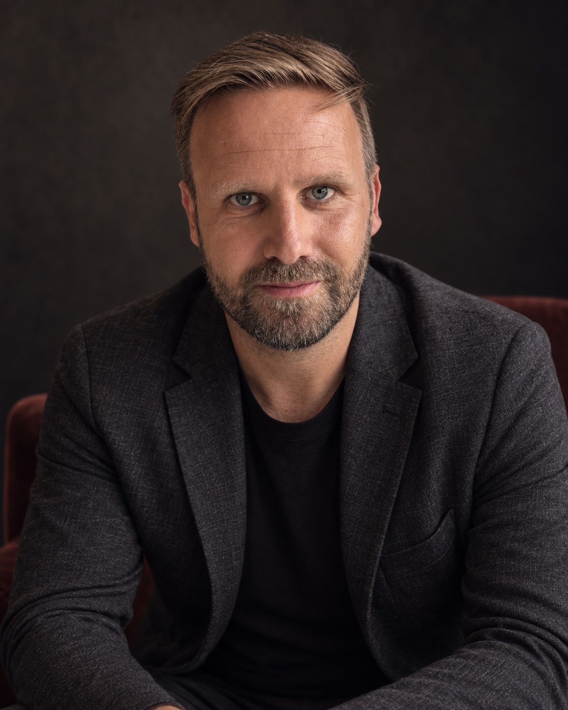 Editorial portrait of Matthias Höfelmeyer, seated in a charcoal jacket with direct eye contact